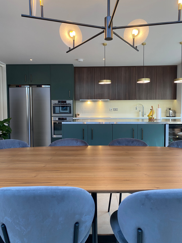 Design ideas for a large contemporary single-wall eat-in kitchen in London with a drop-in sink, flat-panel cabinets, dark wood cabinets, stainless steel benchtops, white splashback, ceramic splashback, stainless steel appliances, porcelain floors, with island, grey floor and grey benchtop.