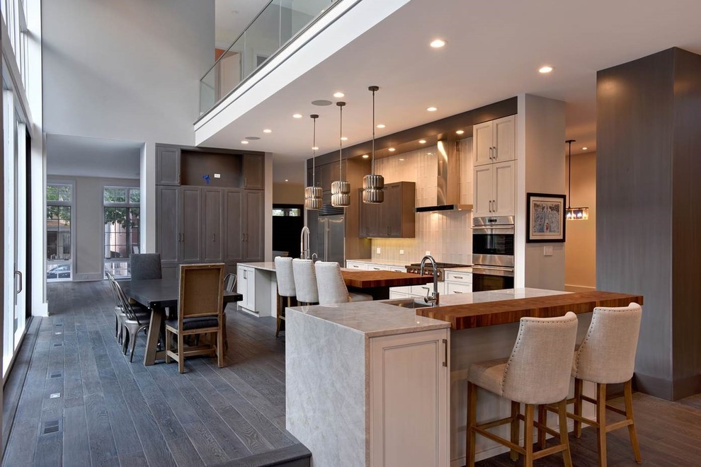 Inspiration for a large transitional u-shaped medium tone wood floor and brown floor eat-in kitchen remodel in Chicago with a double-bowl sink, recessed-panel cabinets, light wood cabinets, quartzite countertops, beige backsplash, glass tile backsplash, stainless steel appliances and two islands