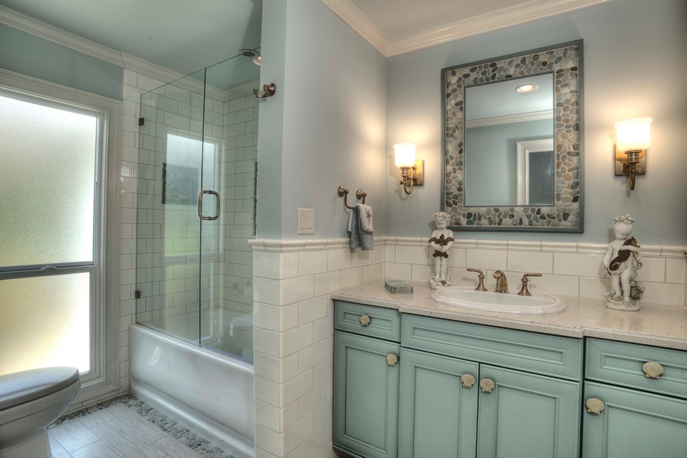 This is an example of a large transitional 3/4 bathroom in Tampa with beaded inset cabinets, turquoise cabinets, an alcove tub, a shower/bathtub combo, white tile, subway tile, blue walls, porcelain floors, a drop-in sink and laminate benchtops.