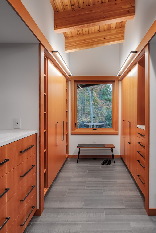Design ideas for a mid-sized country gender-neutral walk-in wardrobe in Minneapolis with flat-panel cabinets, medium wood cabinets, porcelain floors, grey floor and exposed beam.