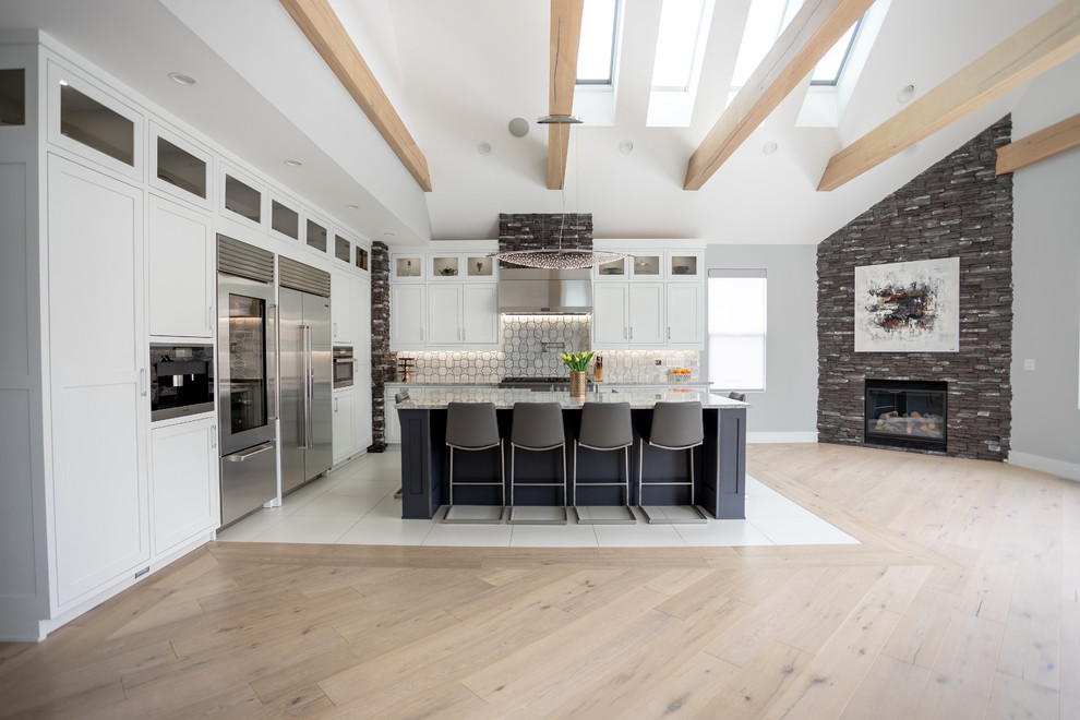 Transitional l-shaped light wood floor and beige floor kitchen photo in Columbus with shaker cabinets, white cabinets, gray backsplash, stainless steel appliances, an island and white countertops