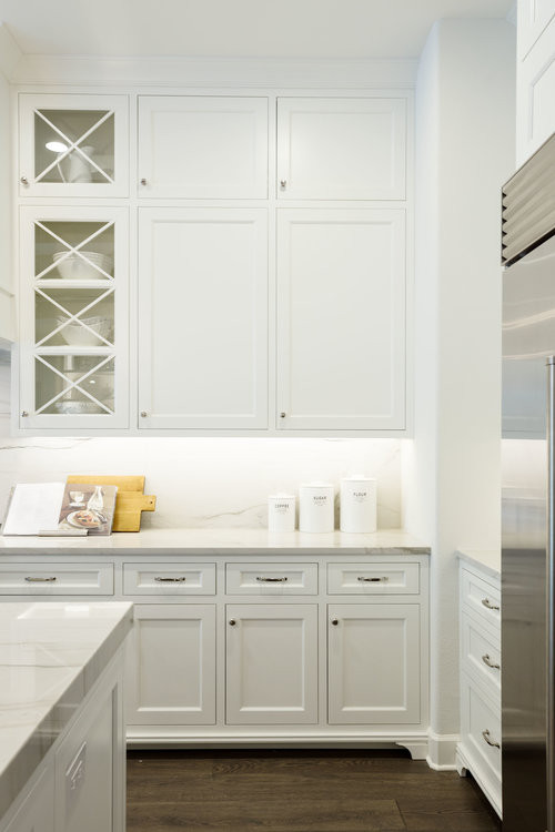Inspiration for a mid-sized transitional single-wall eat-in kitchen in Orlando with a single-bowl sink, recessed-panel cabinets, white cabinets, quartz benchtops, grey splashback, engineered quartz splashback, stainless steel appliances, medium hardwood floors, with island, brown floor, grey benchtop and exposed beam.