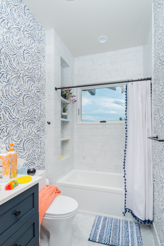Пример оригинального дизайна: маленькая детская ванная комната в стиле неоклассика (современная классика) с фасадами в стиле шейкер, синими фасадами, ванной в нише, душем в нише, раздельным унитазом, белой плиткой, каменной плиткой, синими стенами, мраморным полом, врезной раковиной, столешницей из искусственного камня, белым полом, шторкой для ванной, белой столешницей, нишей, тумбой под одну раковину, встроенной тумбой и обоями на стенах для на участке и в саду