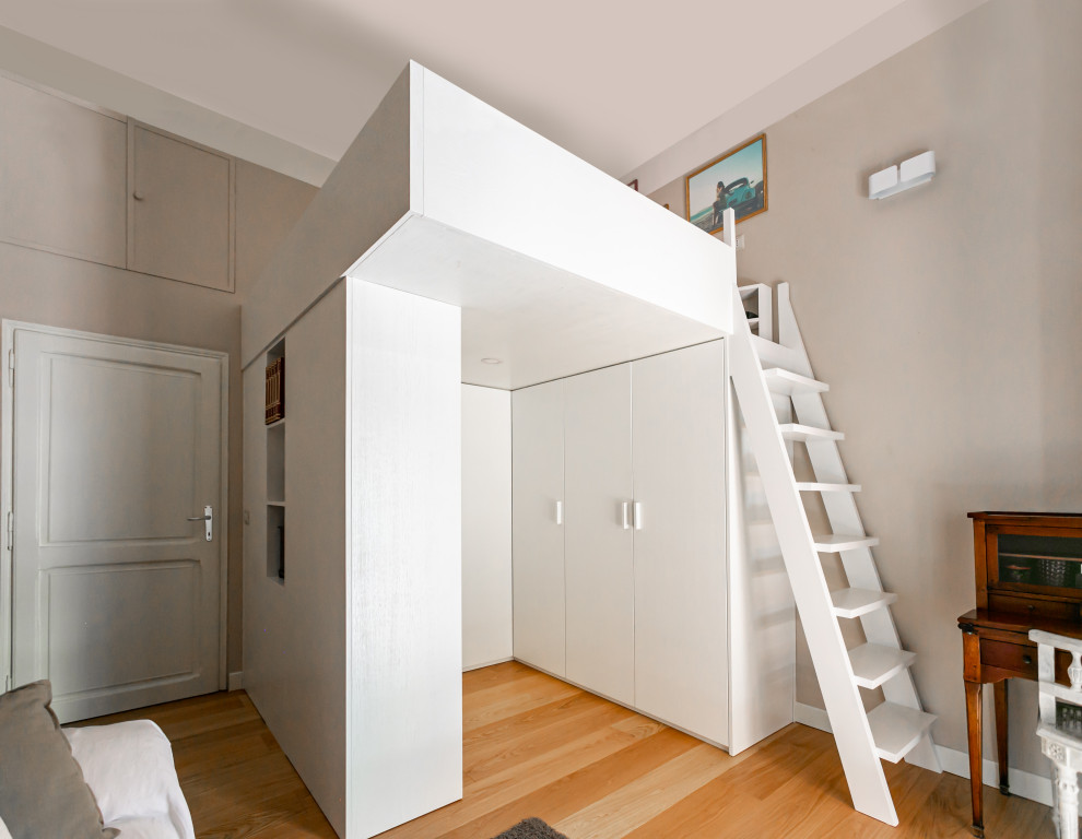 This is an example of a large modern gender neutral kids' bedroom in Rome with beige walls and light hardwood flooring.
