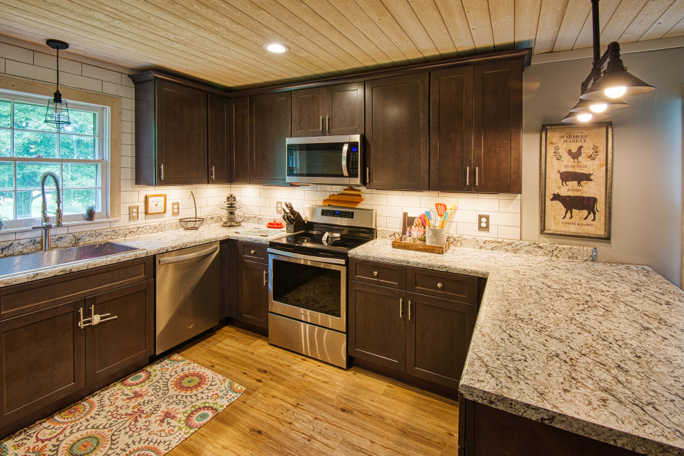 Open concept kitchen - mid-sized transitional u-shaped light wood floor and brown floor open concept kitchen idea with a drop-in sink, shaker cabinets, gray cabinets, laminate countertops, white backsplash, subway tile backsplash, stainless steel appliances, a peninsula and white countertops