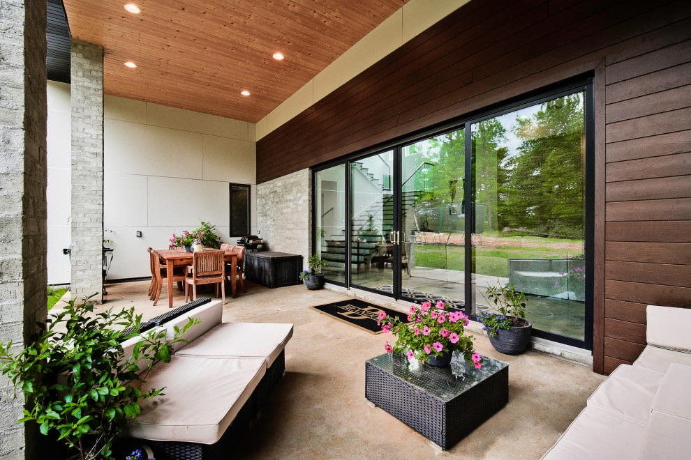 This is an example of a large modern backyard patio in Other with concrete slab and a roof extension.