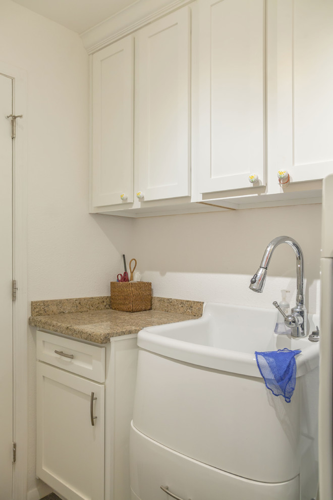 This is an example of a mid-sized transitional galley utility room in Phoenix with an utility sink, recessed-panel cabinets, white cabinets, granite benchtops, yellow walls, carpet, a side-by-side washer and dryer and brown floor.