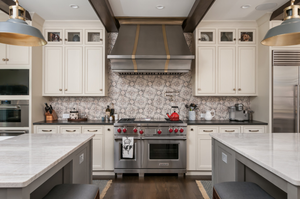 Photo of a large country eat-in kitchen in Atlanta with a farmhouse sink, recessed-panel cabinets, white cabinets, granite benchtops, grey splashback, cement tile splashback, stainless steel appliances, dark hardwood floors, multiple islands, brown floor and white benchtop.