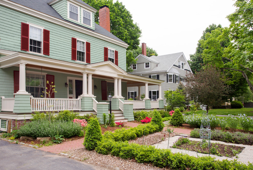 This is an example of a large traditional front yard verandah in Boston with a roof extension and a vegetable garden.