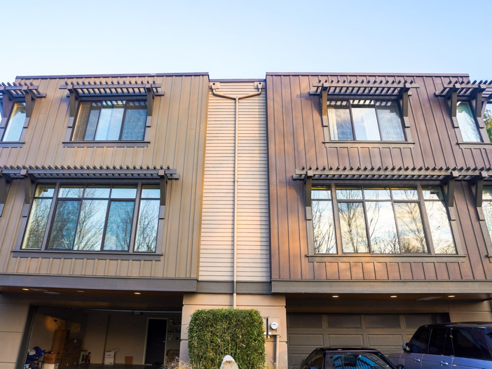 Design ideas for a mid-sized modern three-storey stucco brown townhouse exterior in Seattle with a flat roof, a mixed roof, a brown roof and board and batten siding.
