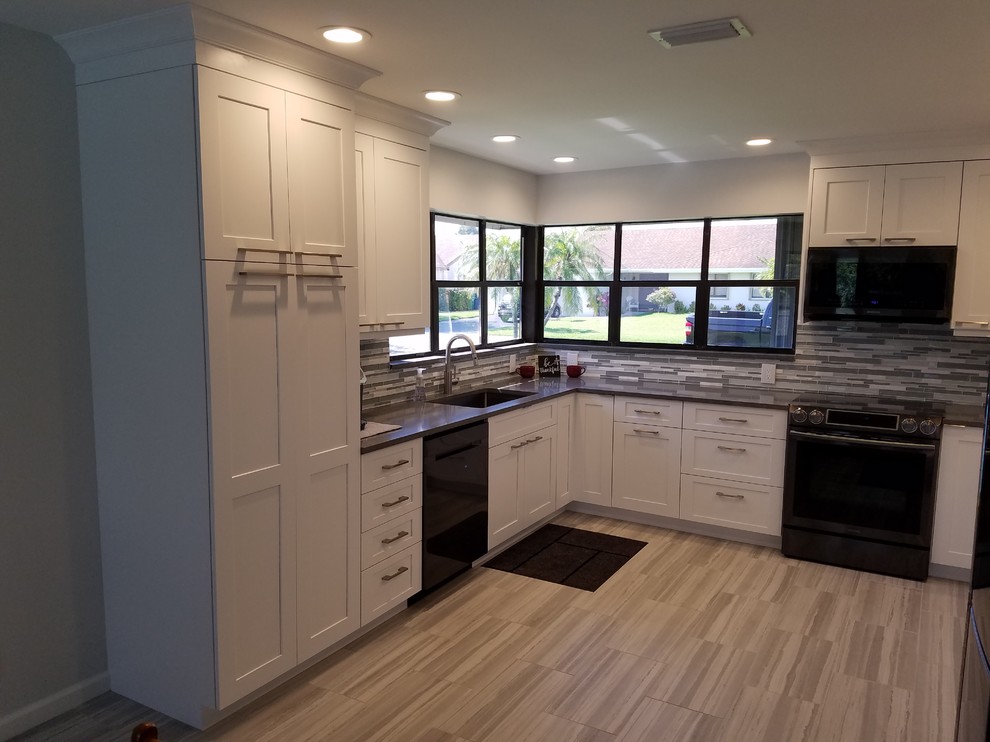 This is an example of a mid-sized contemporary u-shaped kitchen in Miami with an undermount sink, shaker cabinets, white cabinets, quartz benchtops, grey splashback, glass tile splashback, stainless steel appliances, porcelain floors, grey floor and grey benchtop.