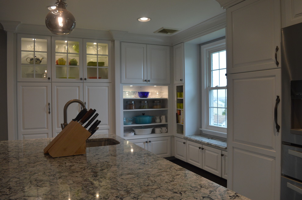 Example of a large transitional u-shaped ceramic tile and gray floor home design design with a farmhouse sink, raised-panel cabinets, white cabinets, quartz countertops, gray backsplash, glass tile backsplash, stainless steel appliances and an island