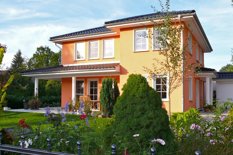 Mittelgroßes, Zweistöckiges Mediterranes Haus mit Putzfassade, gelber Fassadenfarbe und Walmdach in Berlin