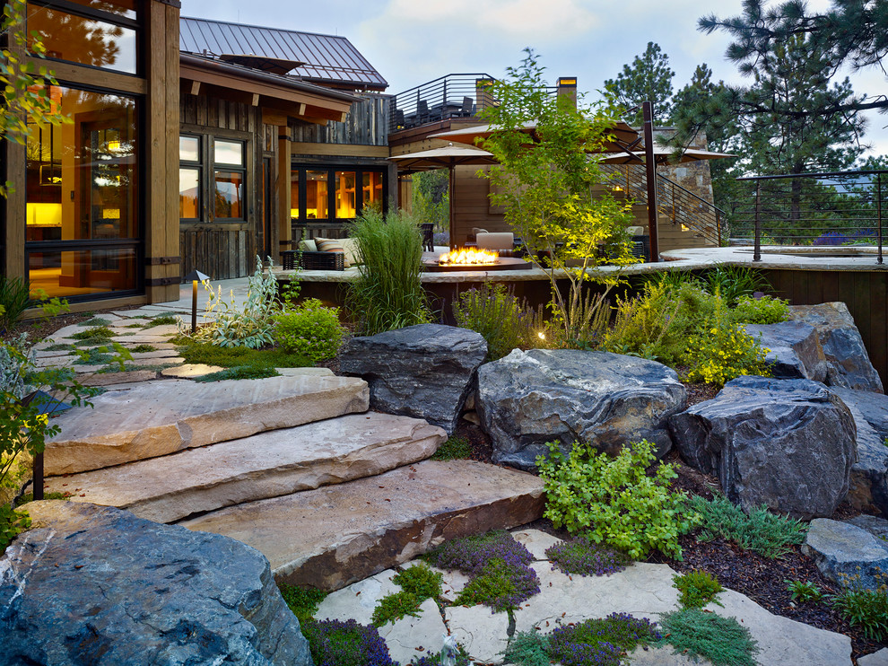 Inspiration for an expansive eclectic sloped xeriscape in Denver with a fire feature and natural stone pavers.