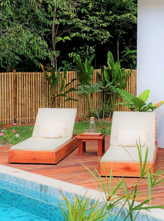 Modelo de terraza planta baja tropical grande en patio y anexo de casas con jardín vertical y barandilla de madera