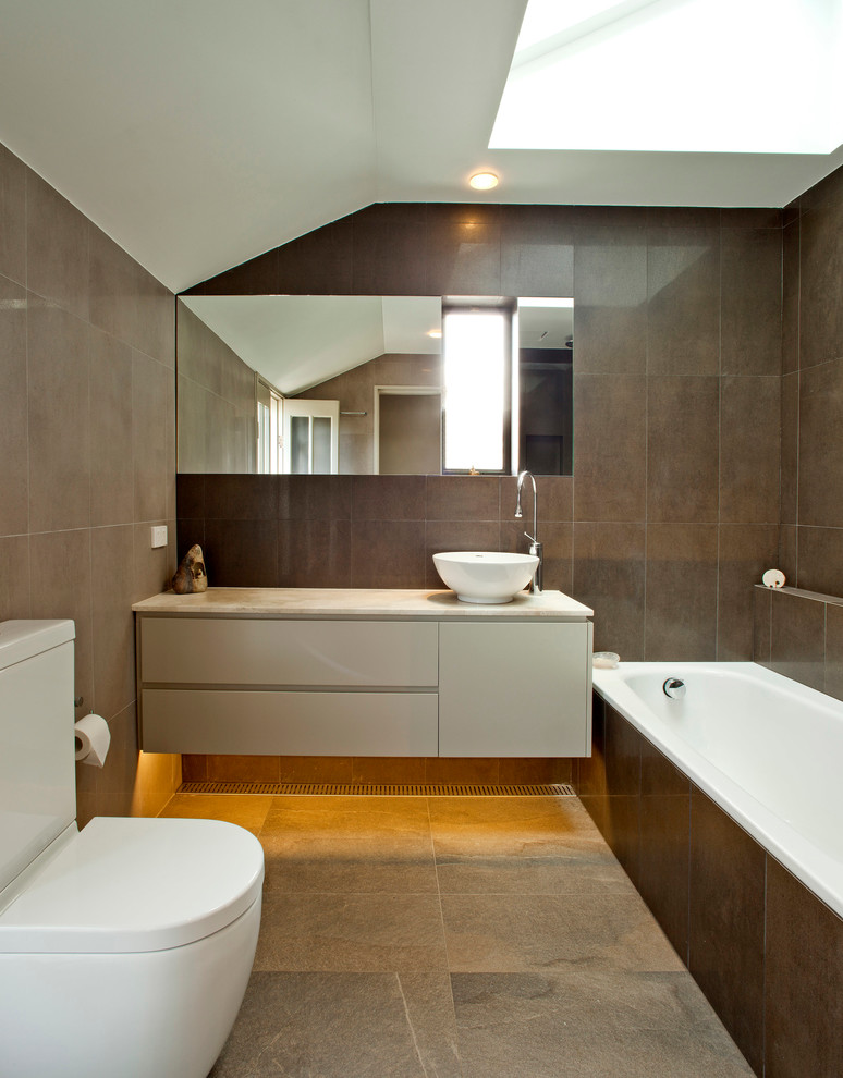 Photo of a large contemporary bathroom in Sydney with beige cabinets, a drop-in tub, brown tile, stone tile and marble benchtops.