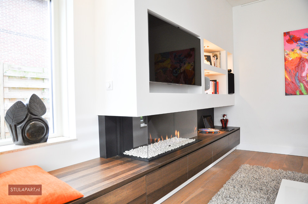 Mid-sized contemporary enclosed living room in Amsterdam with a music area, white walls, dark hardwood floors, a hanging fireplace, a wood fireplace surround and a built-in media wall.