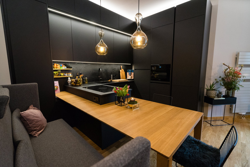 Стильный дизайн: кухня среднего размера в скандинавском стиле с обеденным столом, черными фасадами, островом и бежевым полом - последний тренд