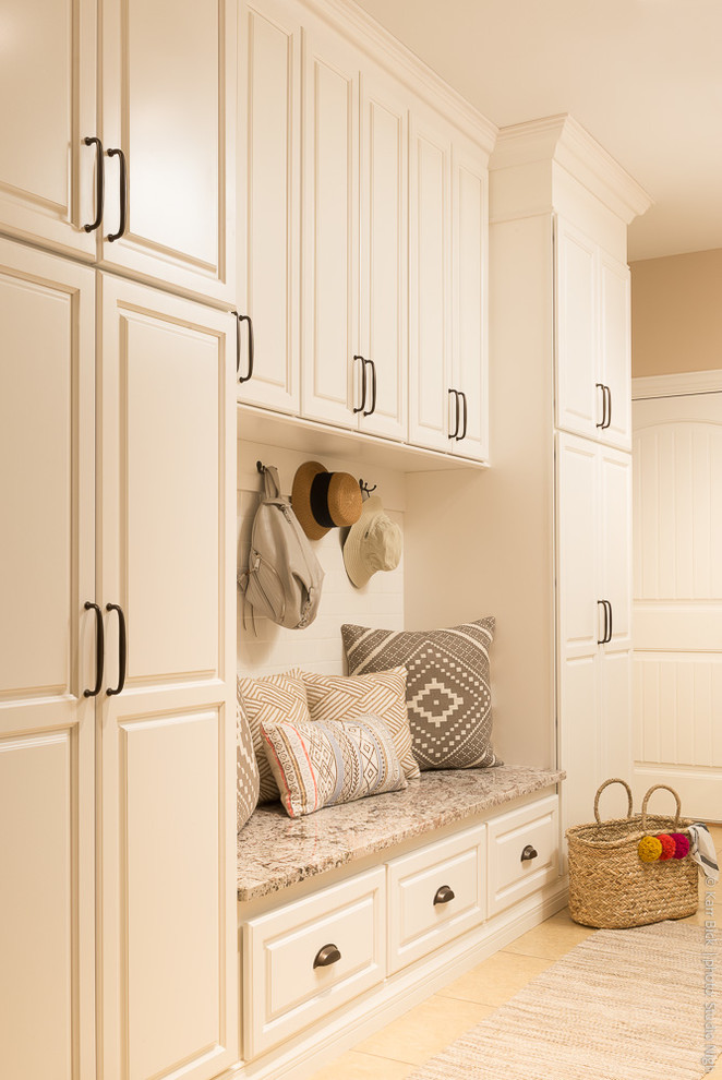 Photo of a mid-sized traditional galley laundry room in St Louis with an undermount sink, raised-panel cabinets, white cabinets, granite benchtops, beige walls, porcelain floors, a side-by-side washer and dryer and beige floor.