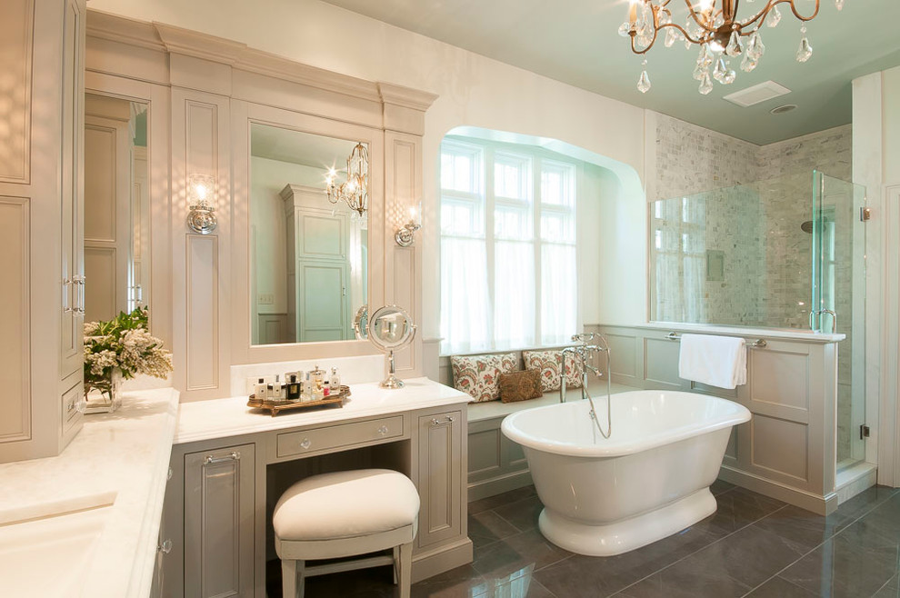 Photo of a large traditional master bathroom in St Louis with beaded inset cabinets, white cabinets, a freestanding tub, a curbless shower, a two-piece toilet, gray tile, stone tile, white walls, porcelain floors, an undermount sink and engineered quartz benchtops.