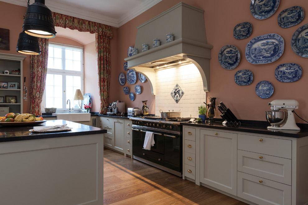 Inspiration for a large country l-shaped open plan kitchen in Cologne with a farmhouse sink, beaded inset cabinets, granite benchtops, pink splashback, ceramic splashback, coloured appliances, medium hardwood floors and with island.