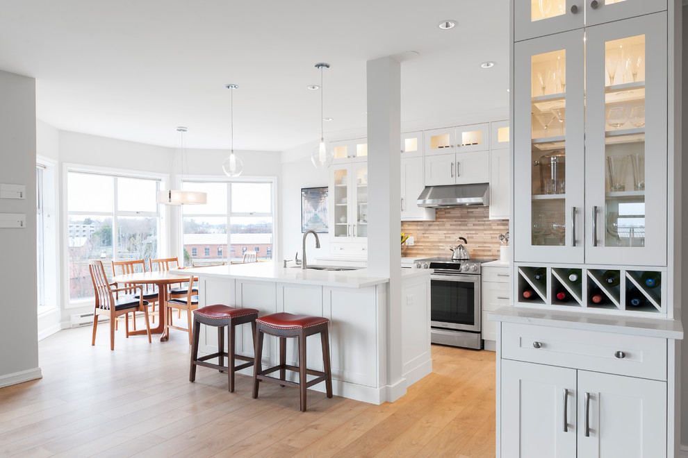 Eat-in kitchen - mid-sized transitional l-shaped laminate floor eat-in kitchen idea in Vancouver with an undermount sink, shaker cabinets, white cabinets, quartz countertops, gray backsplash, glass tile backsplash, stainless steel appliances and an island