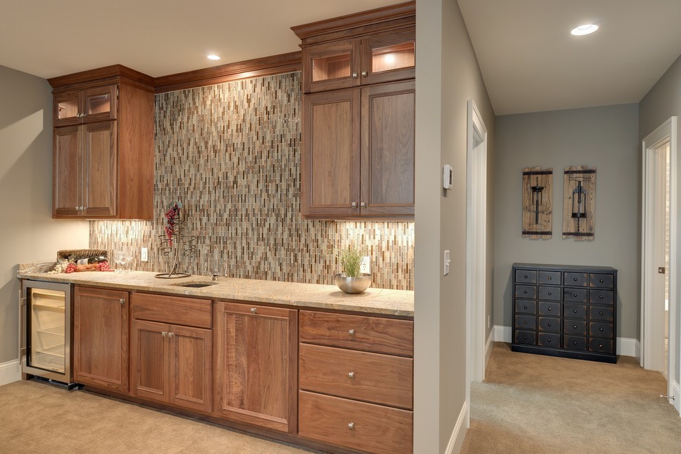 This is an example of an expansive single-wall wet bar in Minneapolis with beaded inset cabinets, medium wood cabinets, granite benchtops, multi-coloured splashback, glass tile splashback and carpet.