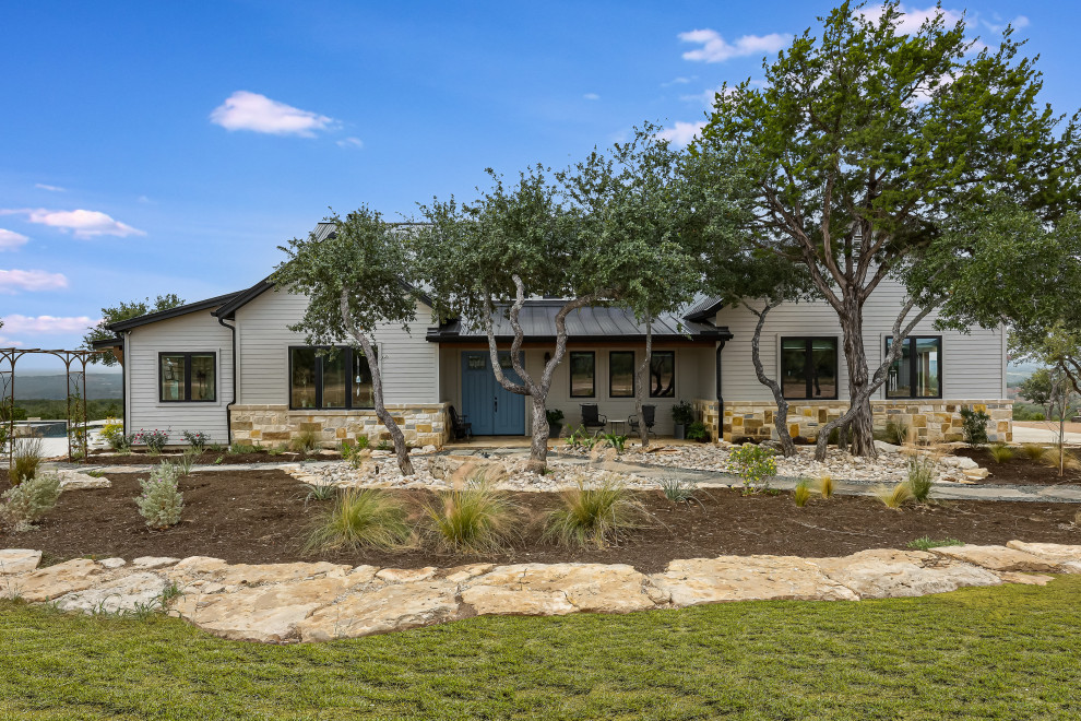 Example of a cottage one-story stone and clapboard exterior home design in Austin with a mixed material roof