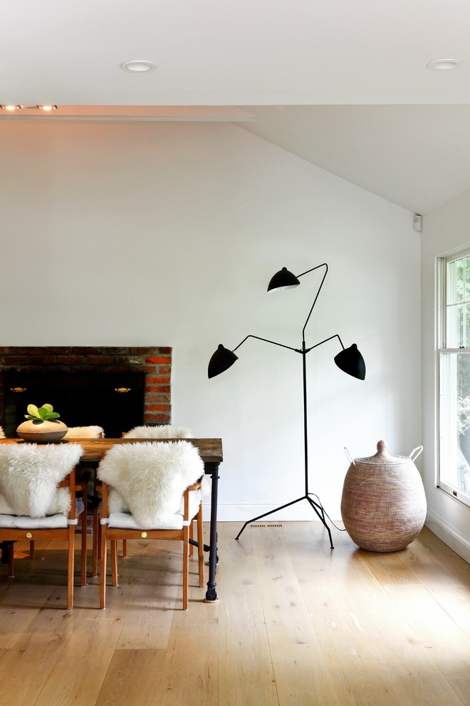 This is an example of a scandinavian dining room in New York with white walls.