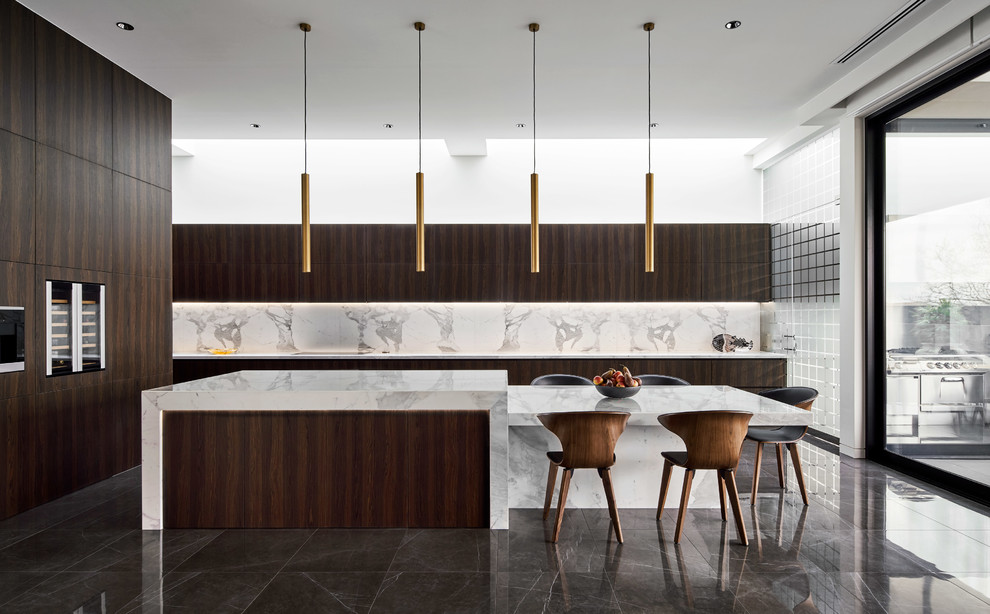 This is an example of an expansive contemporary l-shaped eat-in kitchen in Melbourne with dark wood cabinets, marble benchtops, white splashback, marble splashback, porcelain floors, grey floor, white benchtop, flat-panel cabinets, panelled appliances and with island.