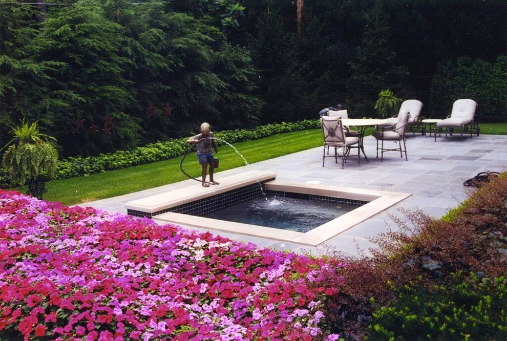 This is an example of a mid-sized traditional backyard full sun formal garden for spring in Detroit with with pond and natural stone pavers.