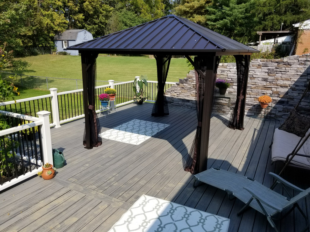 Photo of a large contemporary backyard and ground level deck in Cincinnati with with privacy feature, a pergola and mixed railing.