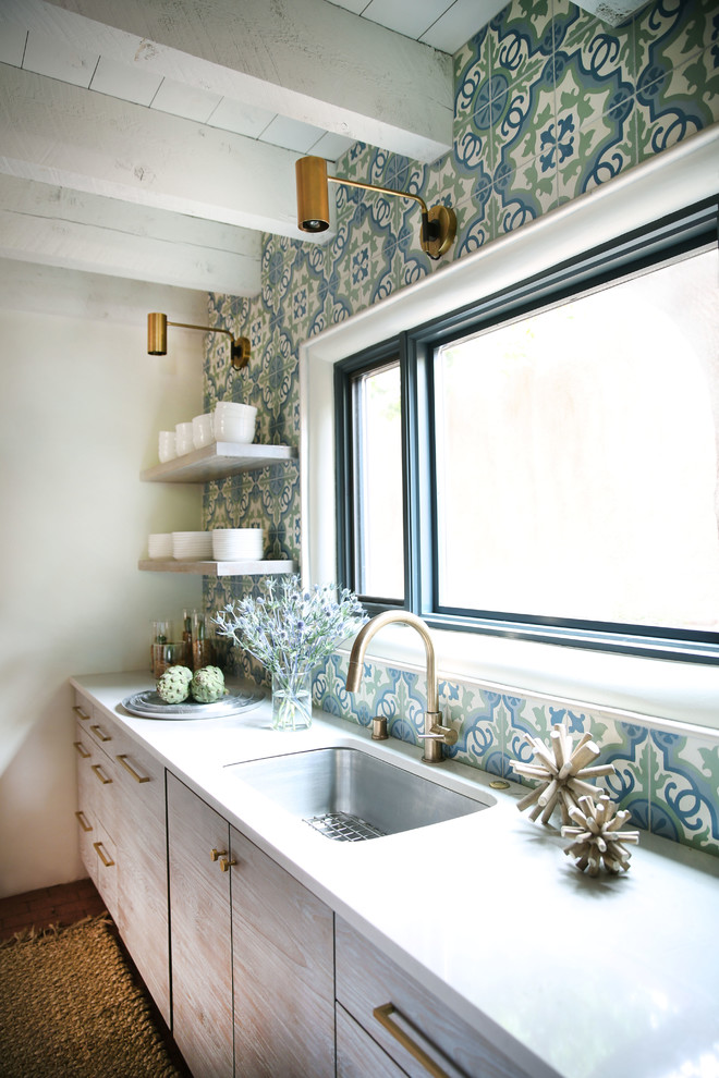 Modern kitchen in Albuquerque with an undermount sink, flat-panel cabinets, white cabinets, quartzite benchtops, blue splashback, cement tile splashback, stainless steel appliances and brick floors.