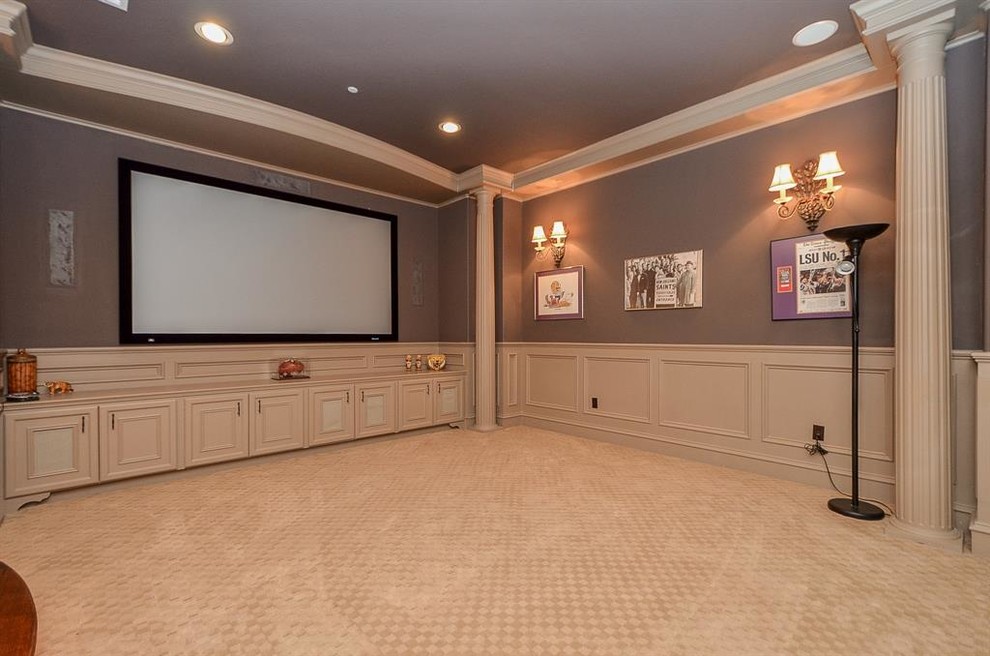 Photo of a large mediterranean enclosed home theatre in Houston with grey walls, carpet, a projector screen and beige floor.