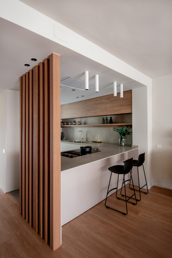 На фото: кухня-гостиная среднего размера в современном стиле с фасадами цвета дерева среднего тона, серым фартуком, черной техникой, полуостровом, серой столешницей и барной стойкой