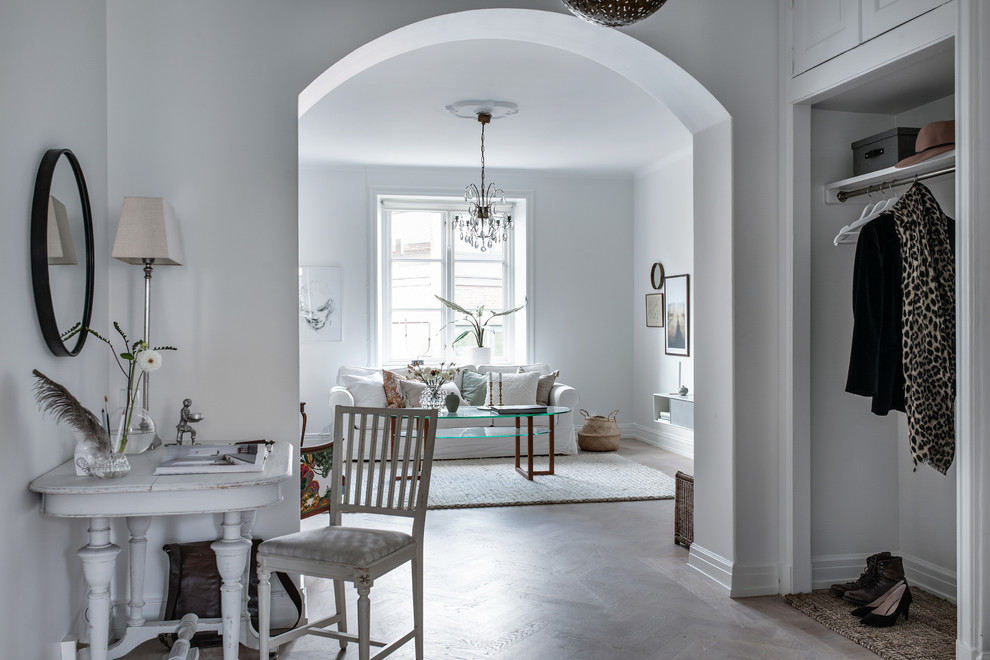Design ideas for a scandinavian entry hall in Gothenburg with white walls, medium hardwood floors and brown floor.