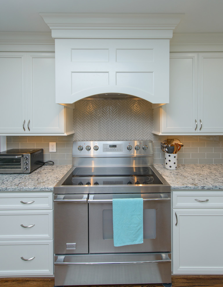 Large transitional l-shaped dark wood floor and brown floor kitchen photo in Baltimore with a farmhouse sink, recessed-panel cabinets, white cabinets, quartz countertops, gray backsplash, subway tile backsplash, stainless steel appliances and an island