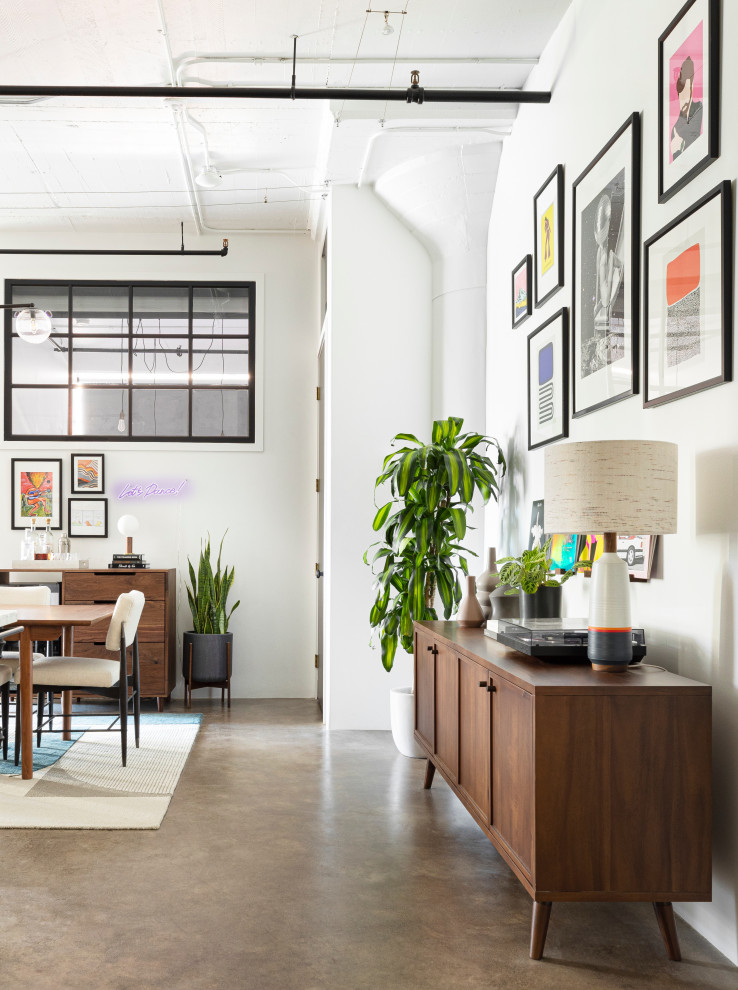 Cette image montre une salle à manger ouverte sur la cuisine urbaine avec un mur blanc, sol en béton ciré et un sol gris.