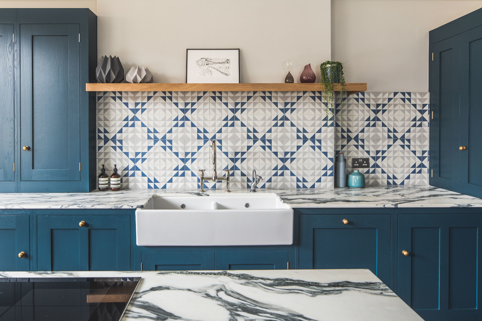 Photo of a large contemporary l-shaped eat-in kitchen in Other with a farmhouse sink, shaker cabinets, blue cabinets, marble benchtops, blue splashback, cement tile splashback, stainless steel appliances, dark hardwood floors, with island and brown floor.