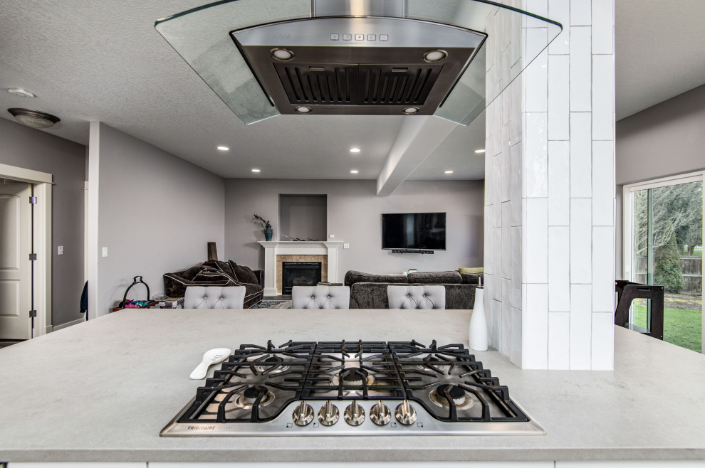 Inspiration for a mid-sized timeless l-shaped vinyl floor and gray floor eat-in kitchen remodel in Portland with an undermount sink, shaker cabinets, white cabinets, solid surface countertops, white backsplash, ceramic backsplash, stainless steel appliances, an island and gray countertops