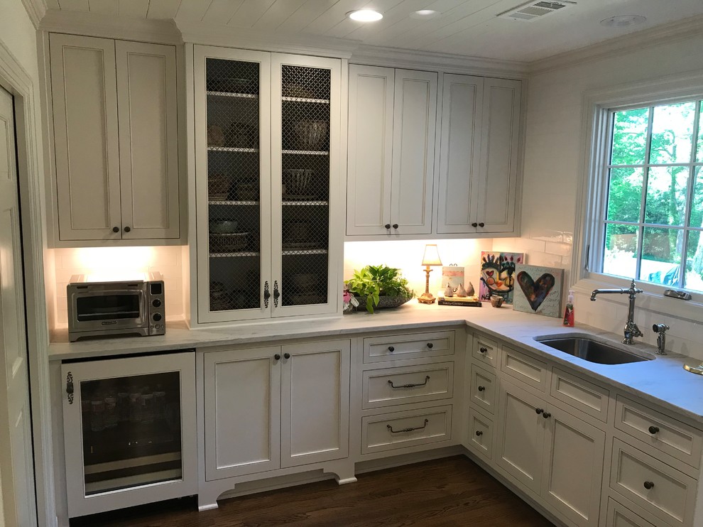 Example of a large transitional u-shaped dark wood floor and brown floor eat-in kitchen design with an undermount sink, recessed-panel cabinets, white cabinets, marble countertops, white backsplash, subway tile backsplash, stainless steel appliances, an island and white countertops