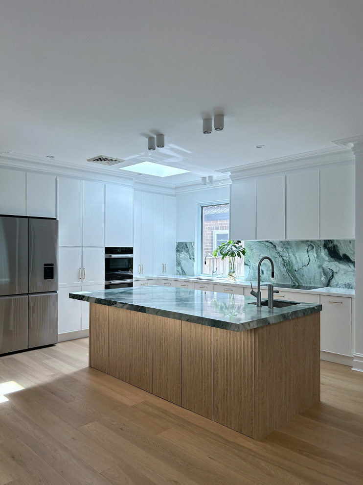 Photo of a large modern l-shaped kitchen pantry in Sydney with a drop-in sink, shaker cabinets, white cabinets, marble benchtops, green splashback, marble splashback, black appliances, light hardwood floors, with island, brown floor and green benchtop.