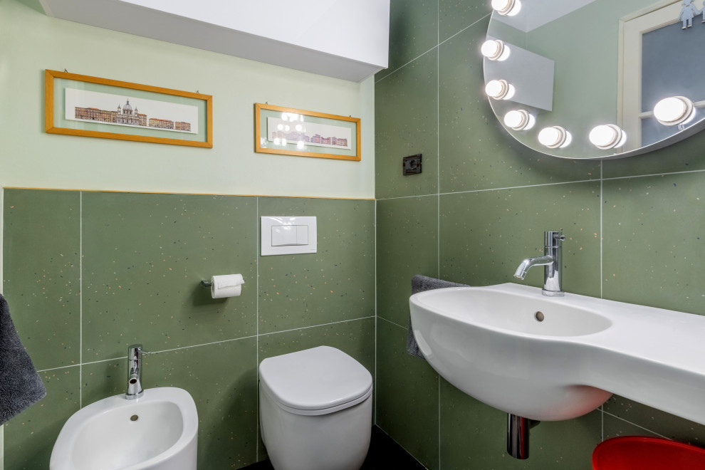Modern inredning av ett litet badrum med dusch, med en kantlös dusch, en vägghängd toalettstol, grön kakel, porslinskakel, gröna väggar, mörkt trägolv, ett väggmonterat handfat, svart golv och dusch med skjutdörr