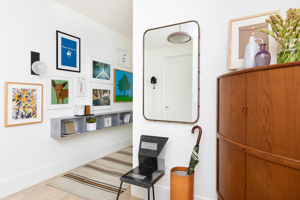 Contemporary entry hall in New York with white walls, light hardwood floors and beige floor.