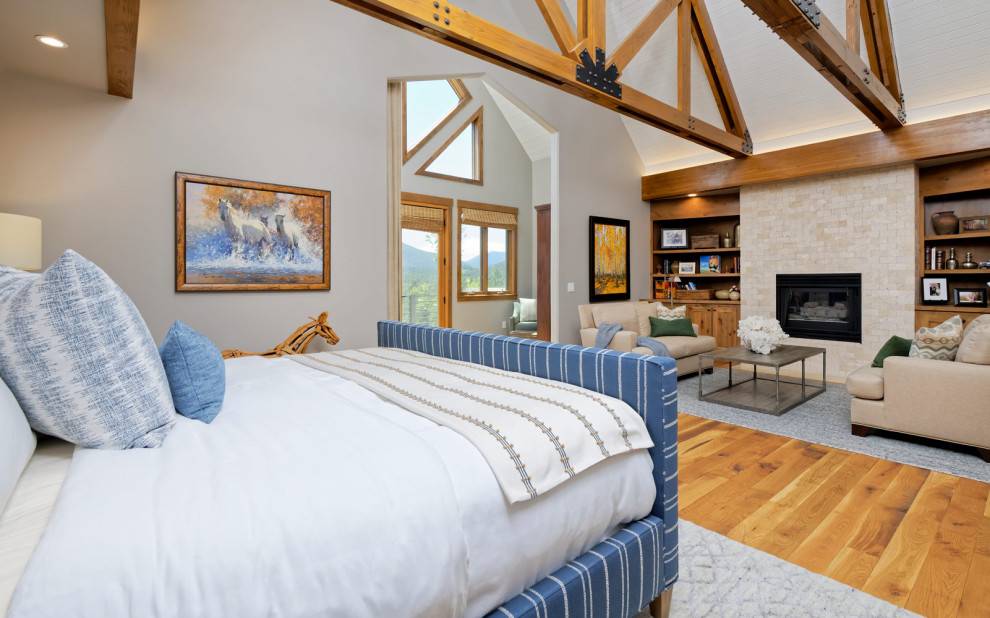 Cette image montre une chambre parentale chalet de taille moyenne avec un mur beige, un sol en bois brun, une cheminée standard et un manteau de cheminée en métal.
