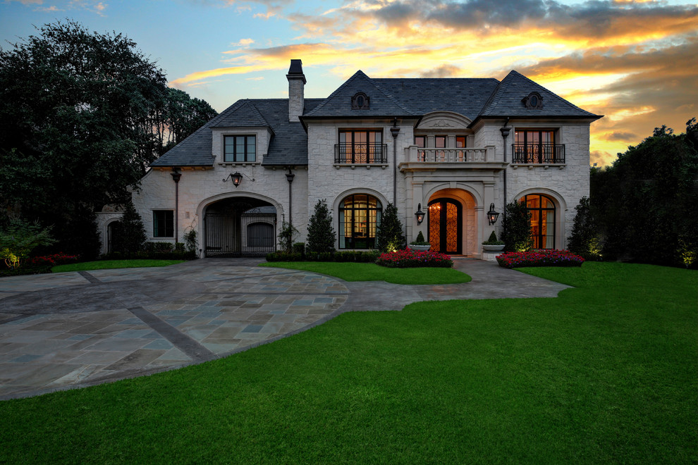 Photo of a traditional two-storey beige house exterior in Dallas with stone veneer, a hip roof and a shingle roof.