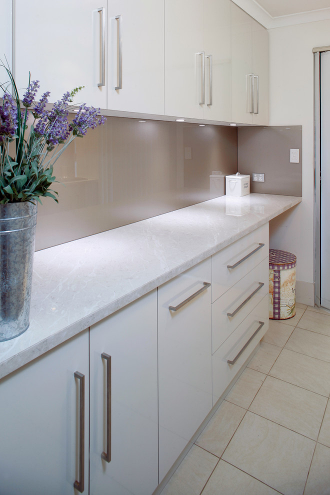 Inspiration for a small contemporary galley dedicated laundry room in Perth with a drop-in sink, flat-panel cabinets, white cabinets, laminate benchtops, ceramic floors, a stacked washer and dryer and white walls.