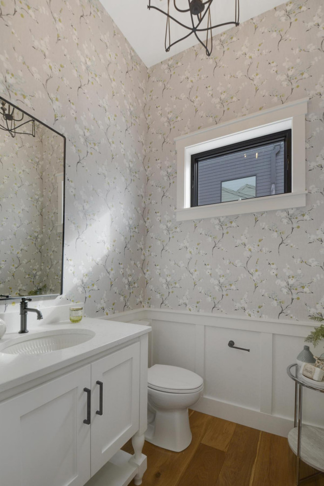 Bathroom in Minneapolis with flat-panel cabinets, white cabinets, light hardwood flooring, a submerged sink, engineered stone worktops, white worktops, a single sink, a freestanding vanity unit and wallpapered walls.