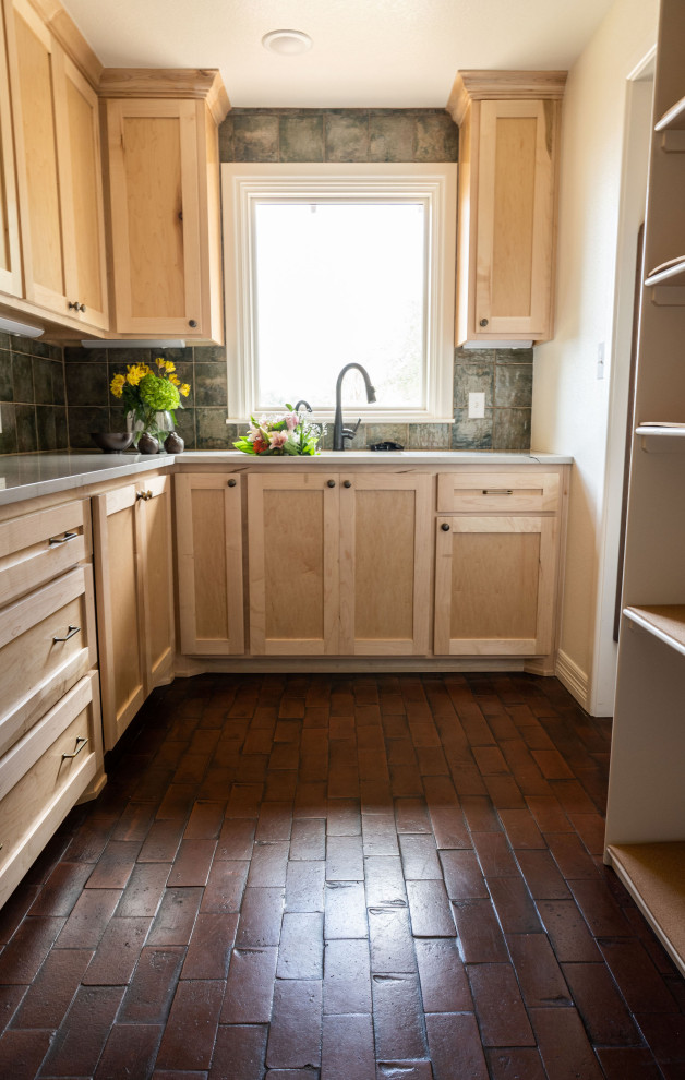 Exemple d'une cuisine en bois clair avec un évier encastré, un placard à porte shaker, un plan de travail en quartz, une crédence verte, une crédence en céramique, un électroménager en acier inoxydable, un sol en brique, un sol rouge et un plan de travail blanc.