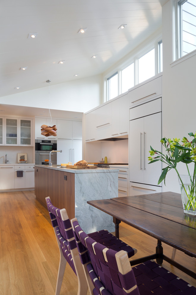 Contemporary u-shaped eat-in kitchen in San Francisco with a drop-in sink, flat-panel cabinets, white cabinets, marble benchtops and stainless steel appliances.